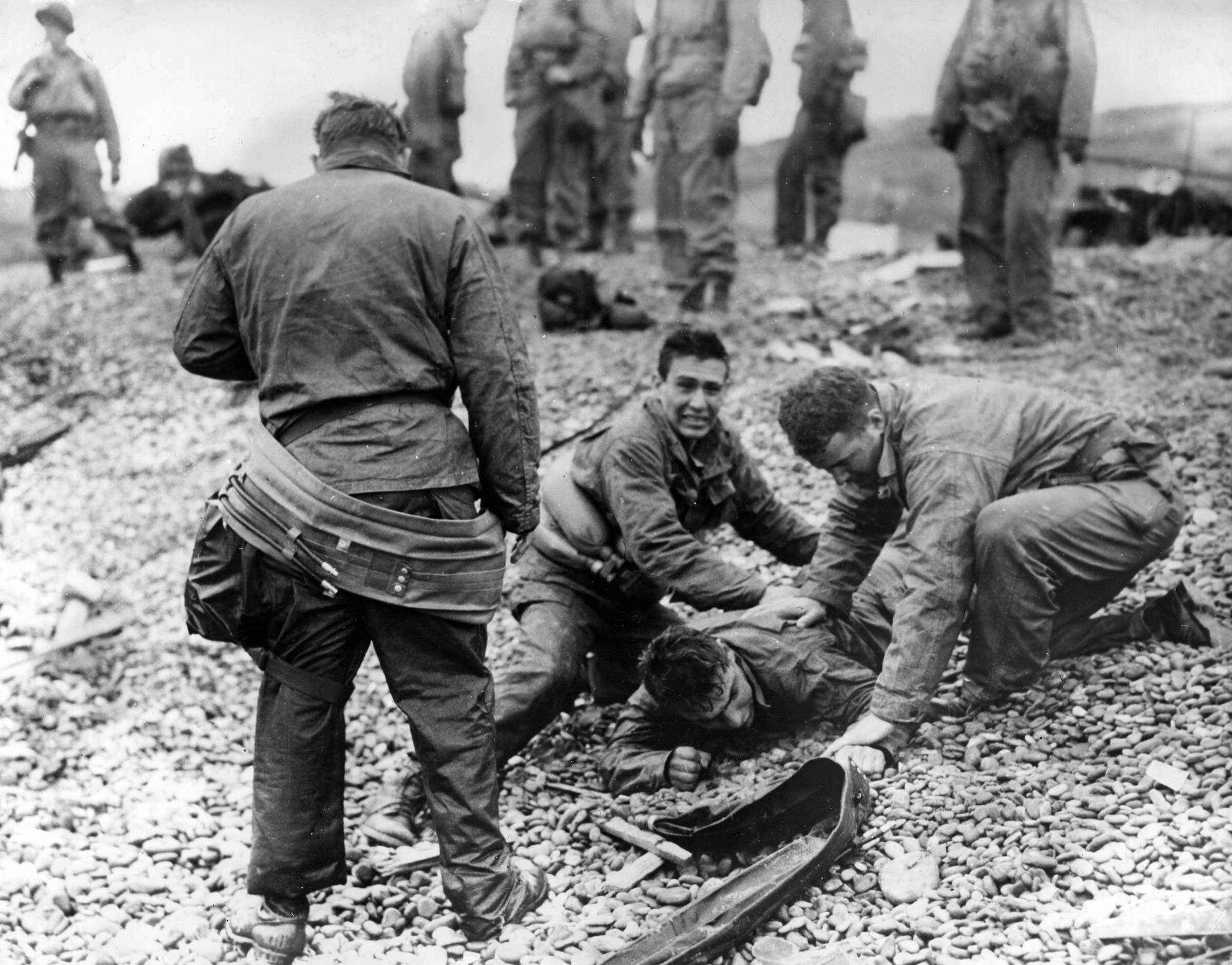 Soldiers providing artificial respiration to a fellow soldier who almost drowned on Omaha Beach